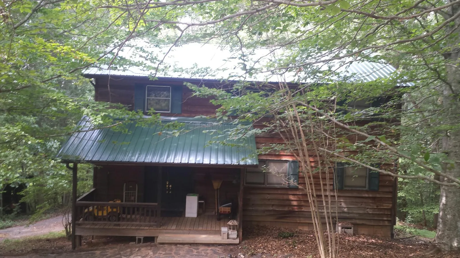 Green metal roof and covered porch on a log cabin in Pisgah