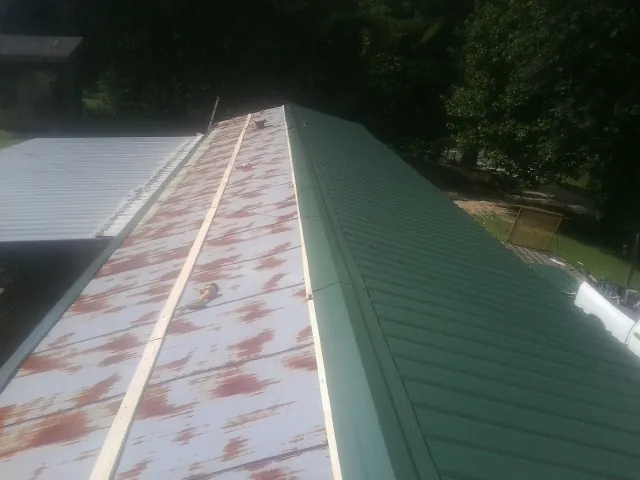 Old rusted panels beside newly installed green metal roofing — Wind Damage Roof Repair by Roofing Brothers in Pisgah