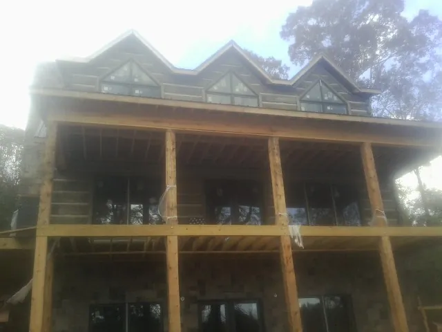 Dormers and porch framing on a large log home under construction — Roof Coating work by our crew in Pisgah