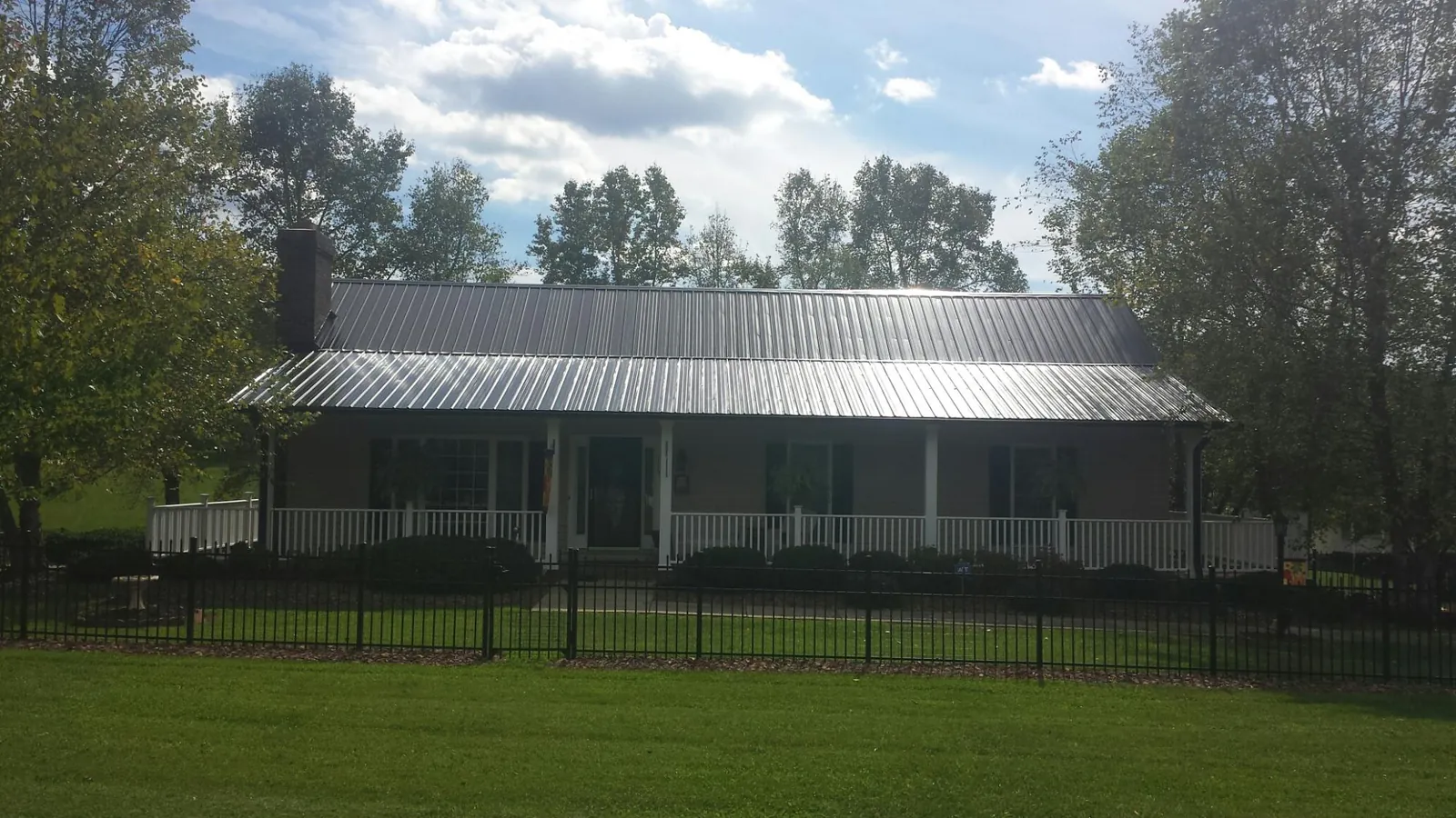 Gray metal roof on a brick ranch with a full width front porch — Gutter Guard Installation work by our crew in Pisgah