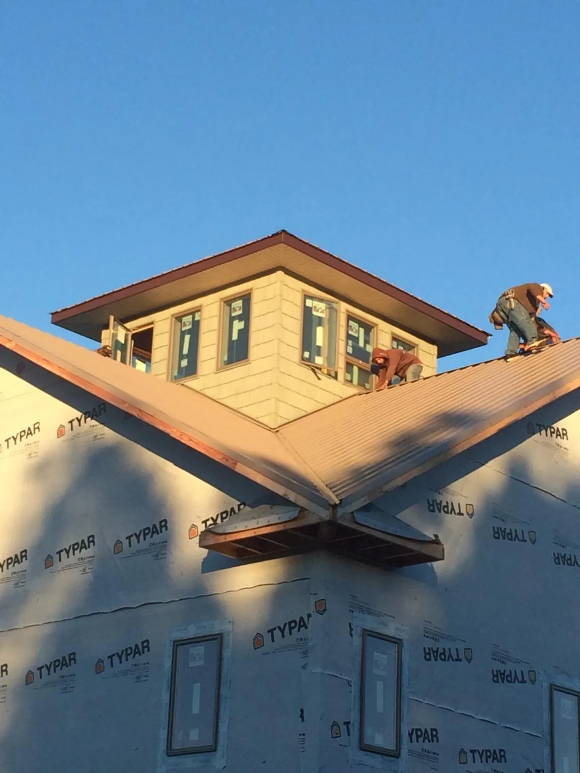 Roofers working around a rooftop cupola on a new metal roof at sunset — Roof Waterproofing in Pisgah by Roofing Brothers